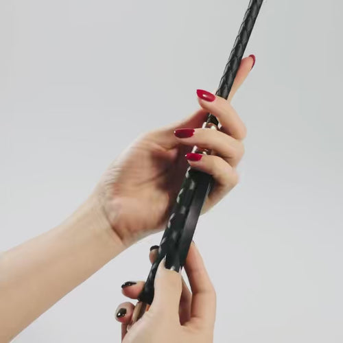 Close-up of black leather riding crop handle showing refined craftsmanship